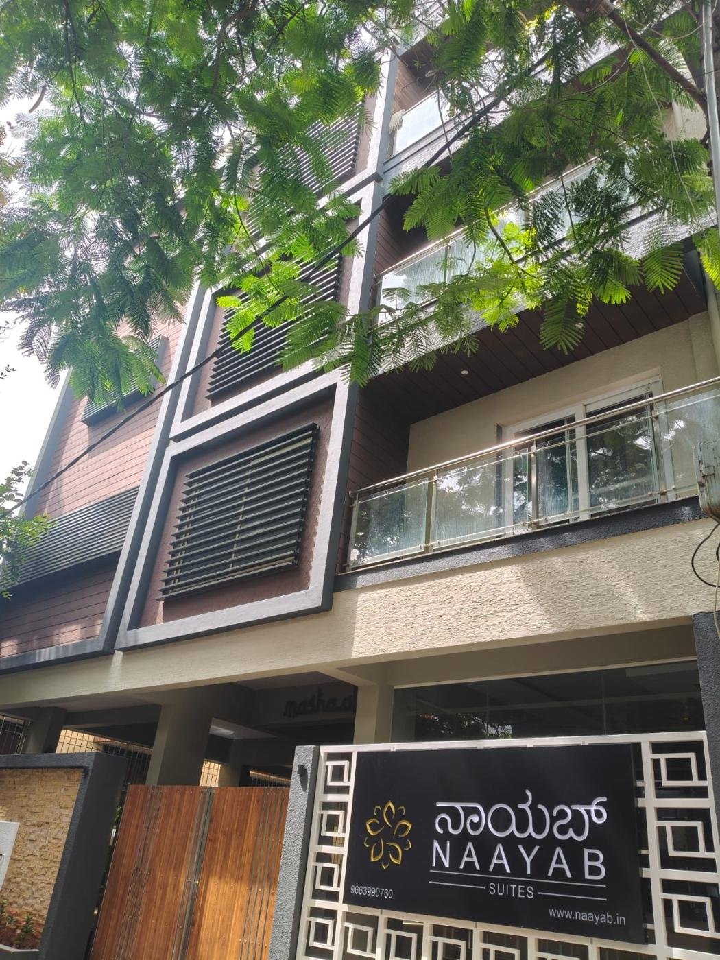 Naayab Suites building under a canopy of trees
